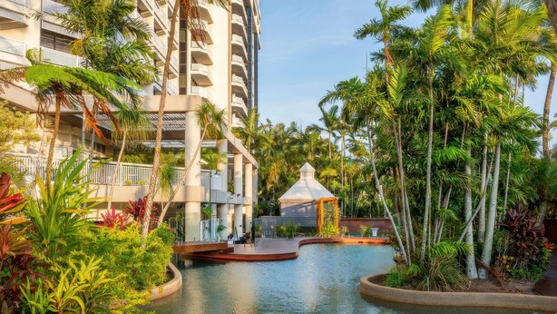Un hotel con piscina rodeado de exuberante vegetación y palmeras.