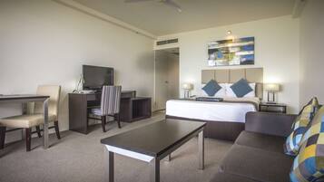 A hotel room with a bed, a desk with a computer, a chair, a sofa, and a coffee table.