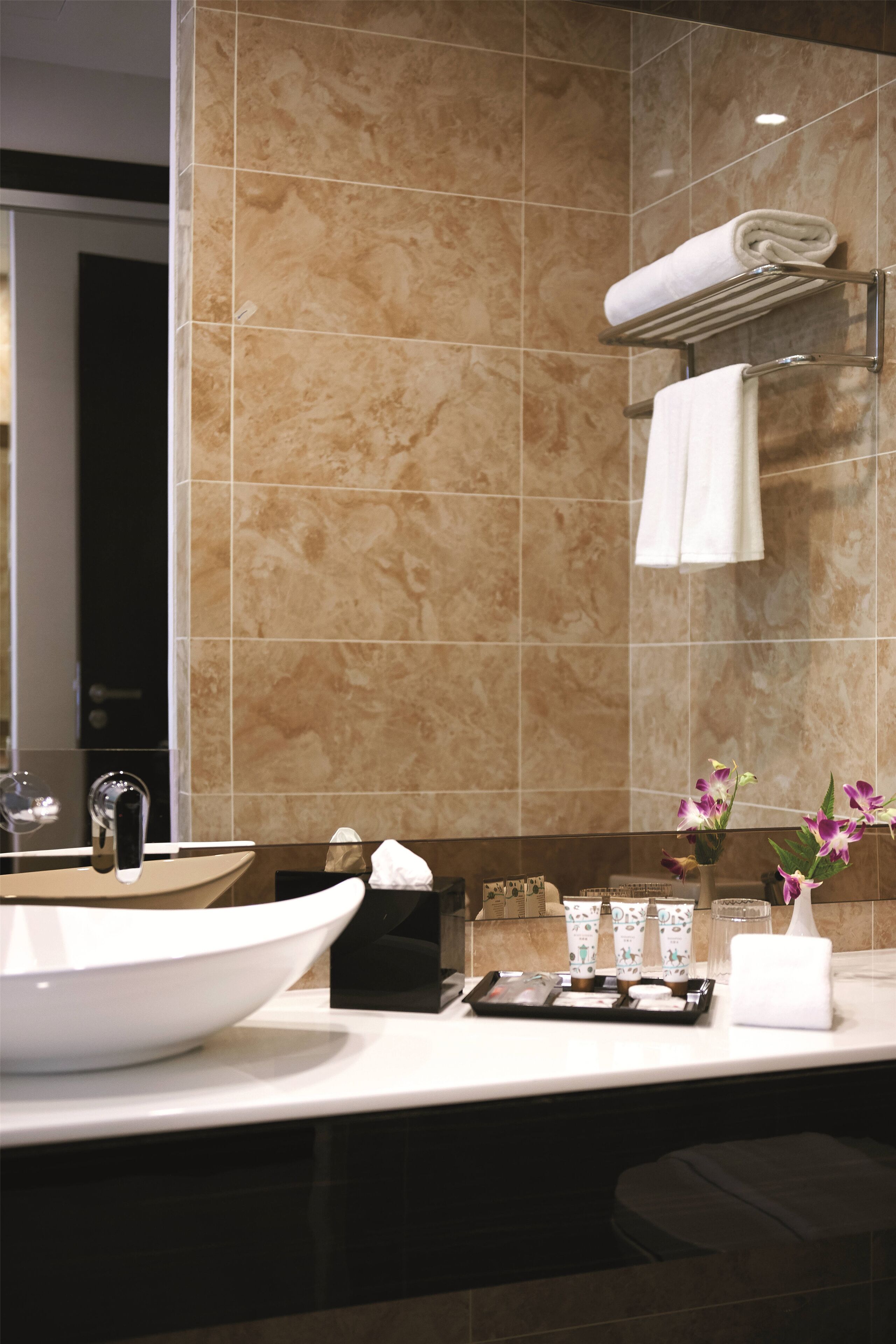 A modern bathroom with a large white sink, a towel rack, and a mirror.