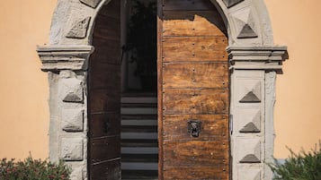 A stone archway with a wooden door, leading to a staircase.