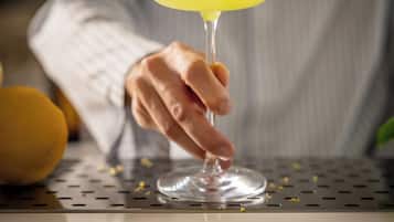 Una persona sosteniendo una copa de cóctel con líquido amarillo y crema batida.