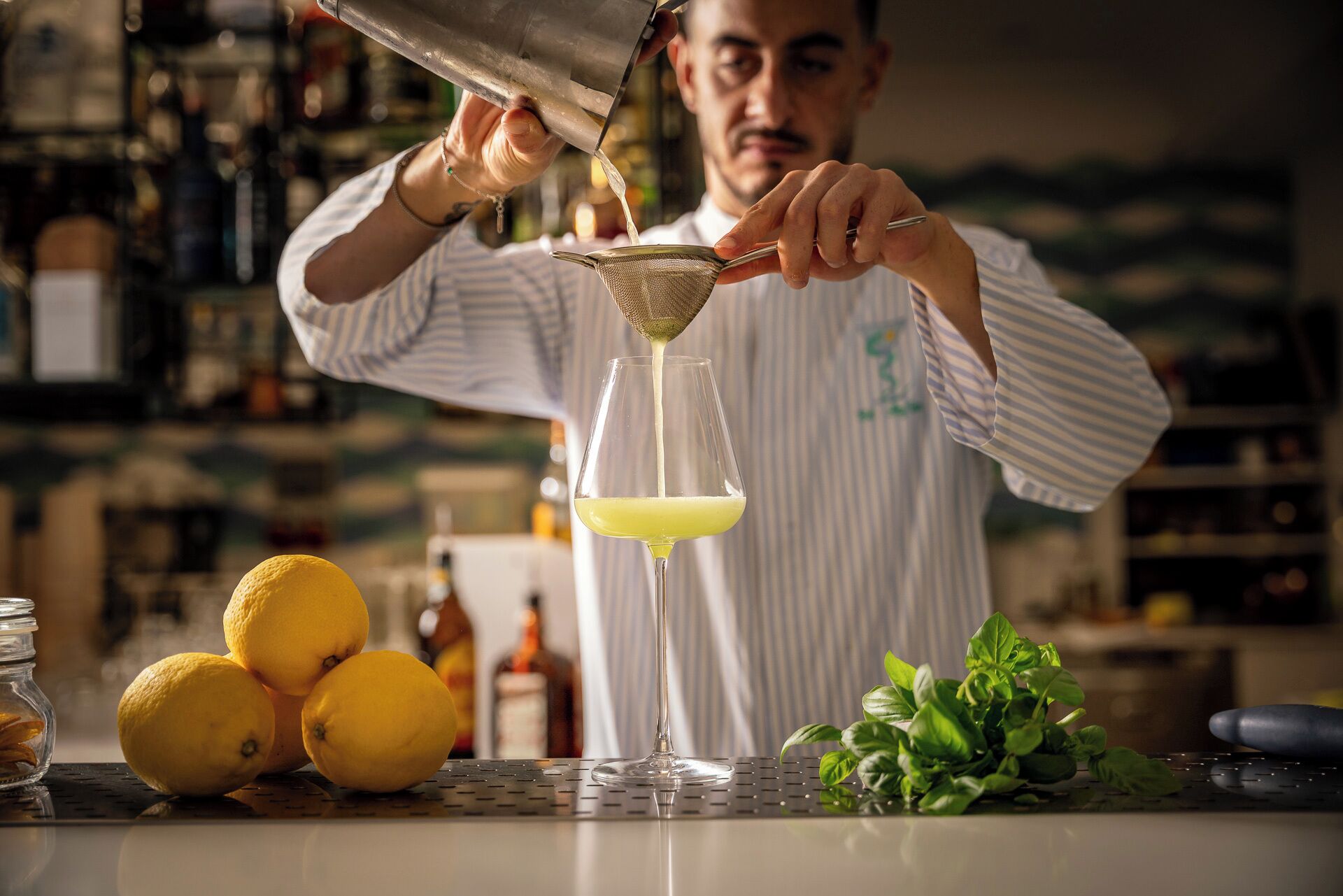 A bartender pouring a drink into a glass.