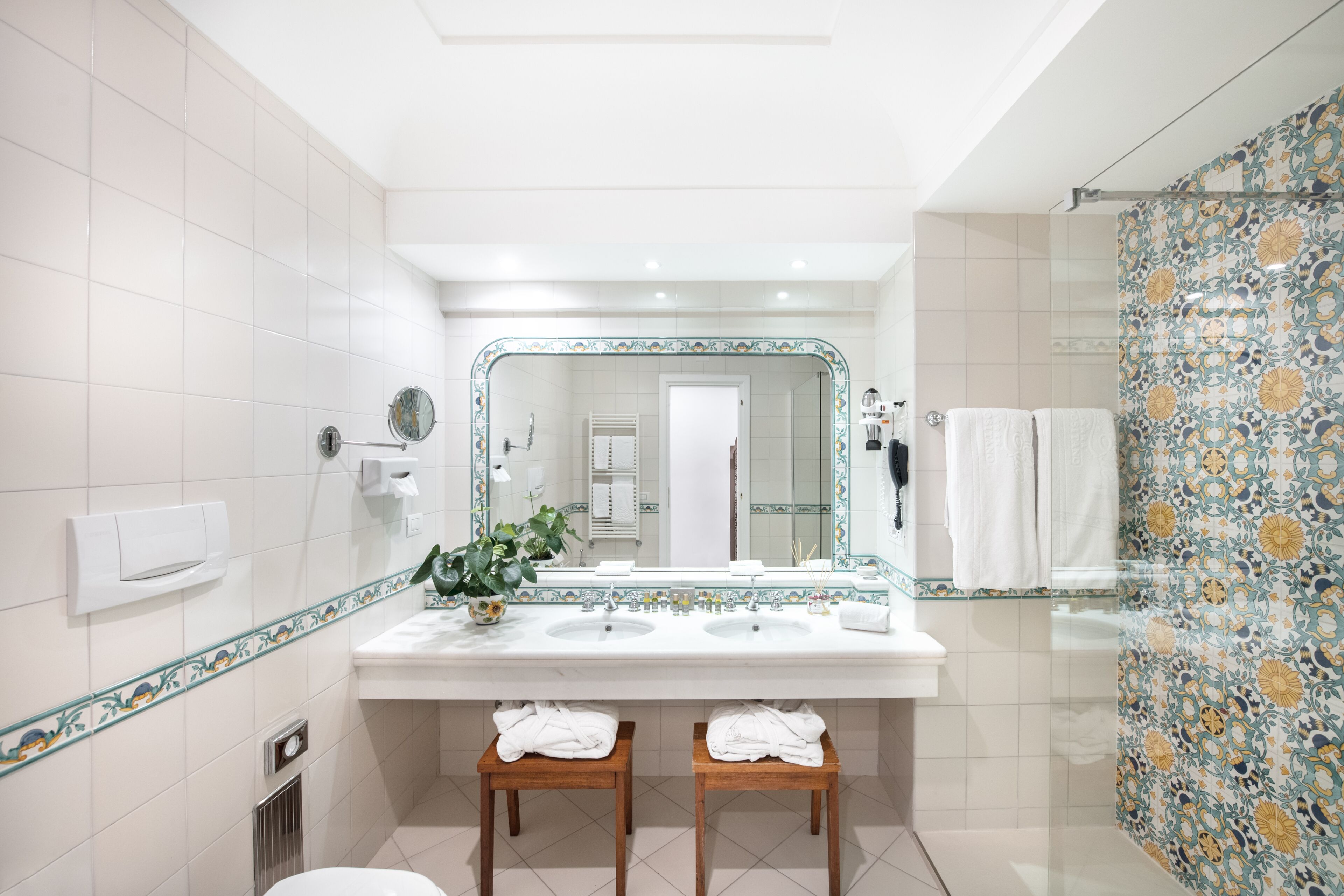 A modern bathroom with two sinks, a large mirror, and a shower area.