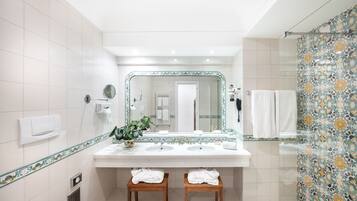 A modern bathroom with two sinks, a large mirror, and a shower area.