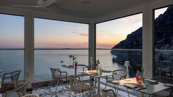 Un espace repas offrant une vue sur la mer et sur une côte montagneuse.