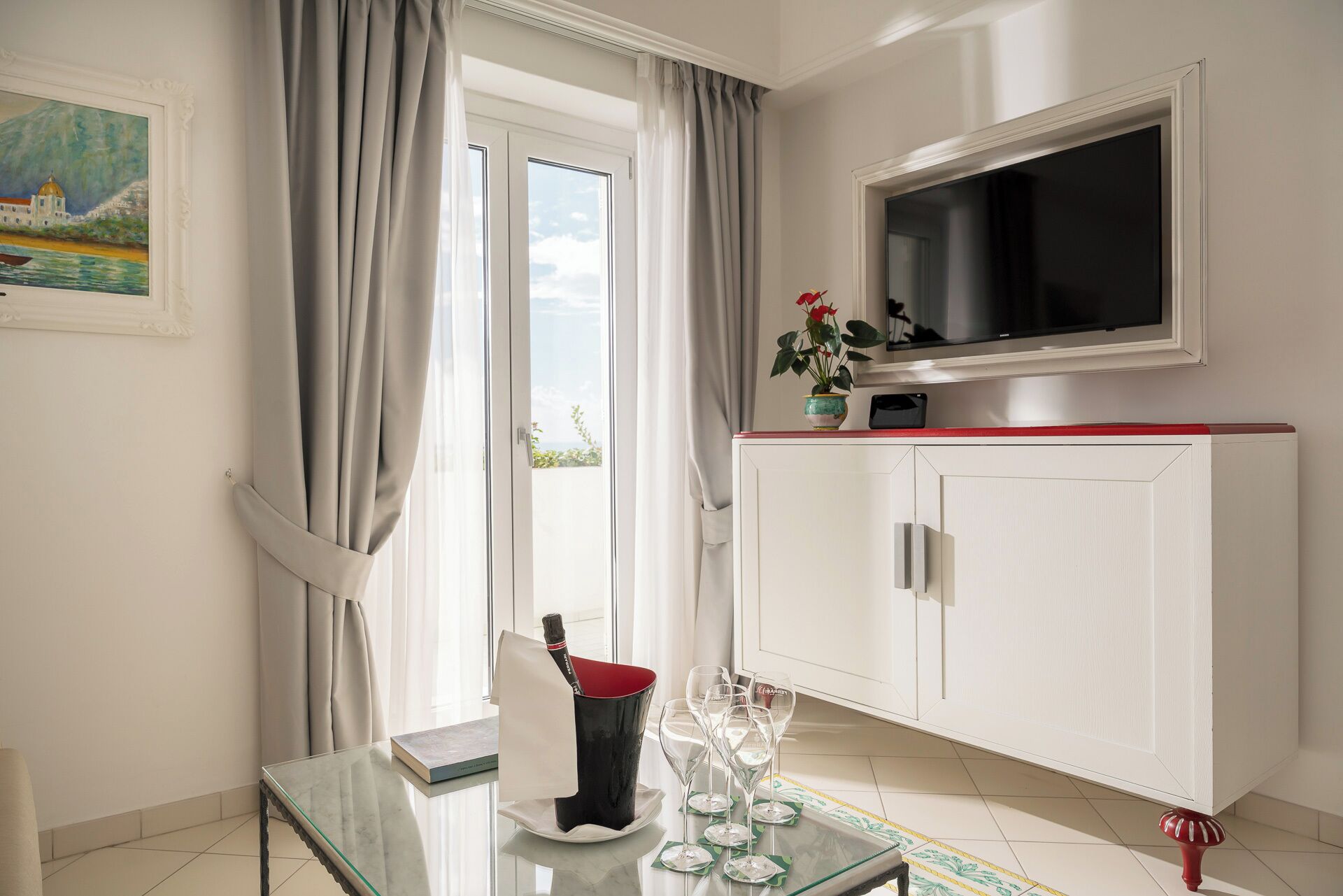 A modern room with a glass table, a TV, a cabinet, and a window with curtains.