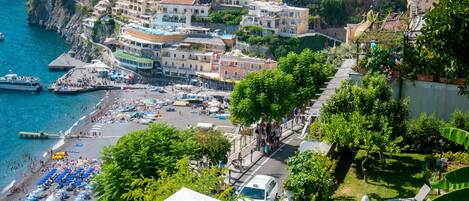 A coastal town with colorful buildings, a beach with sun loungers and umbrellas, and a hot tub.