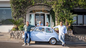 Un coche antiguo estacionado frente a un edificio con un letrero que dice 'Eden Roc'.