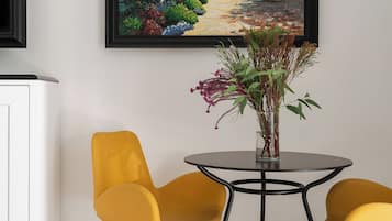 Ein Essbereich mit einem runden Tisch, zwei gelben Stühlen und einer Vase mit Blumen.