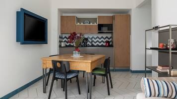 Una cocina compacta con una mesa de madera, sillas y un televisor montado en la pared.