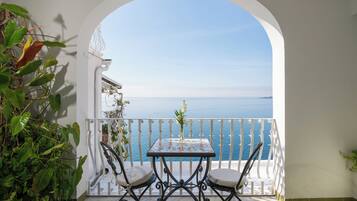 A balcony with a table and chairs, overlooking a sea view.