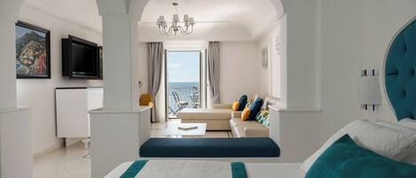 A hotel room with a bed, a TV, a sofa, and a balcony with a view.