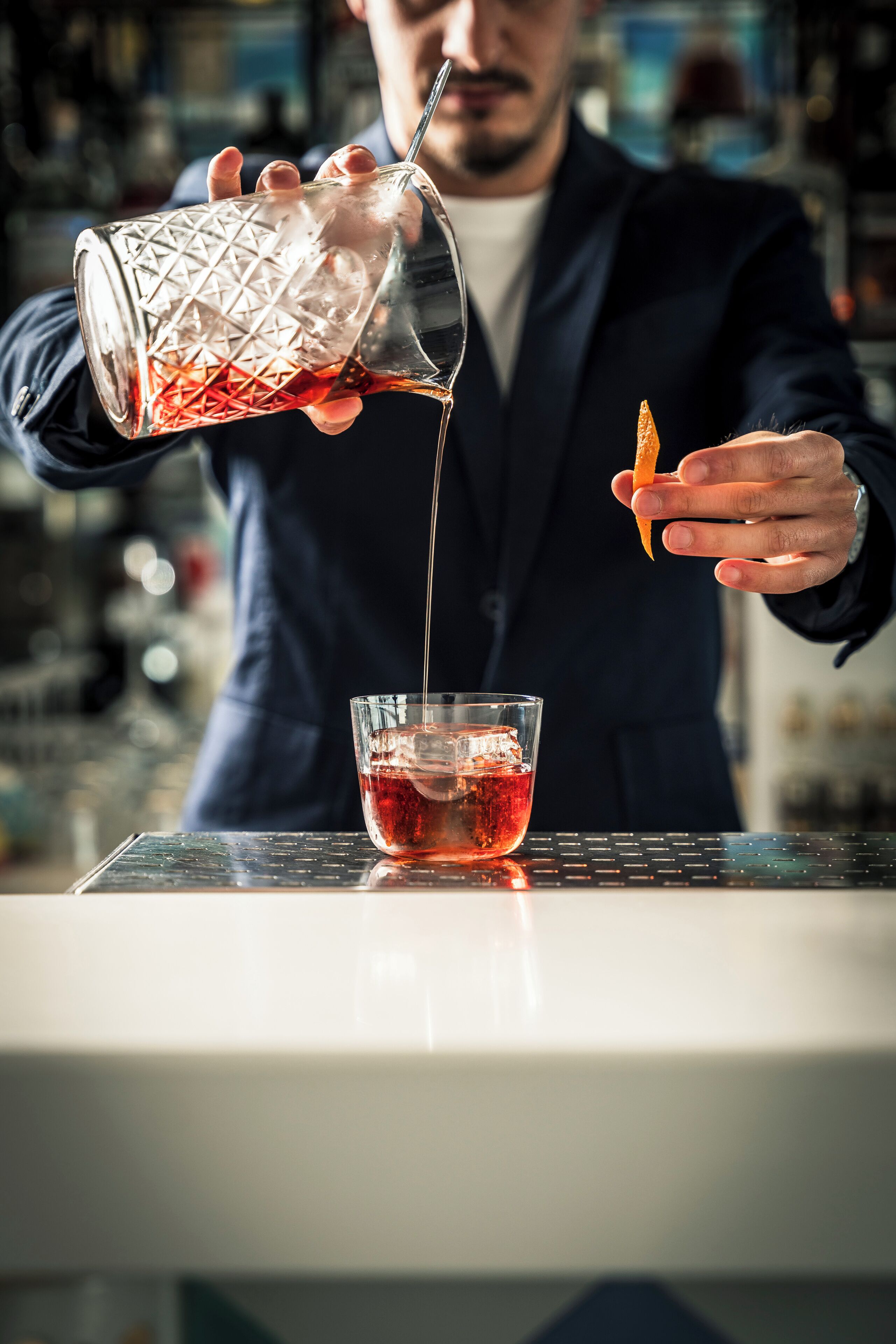 Un barman verse une boisson dans un verre rempli de glaçons.