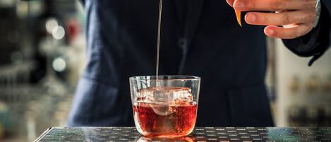 A bartender pouring a drink into a glass with ice.