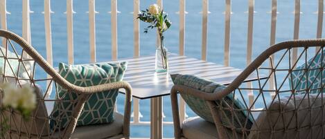 A balcony with wicker furniture, a small table, and a vase with flowers.