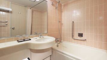 A bathroom with a sink, mirror, shower, and grab bars.