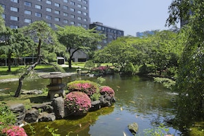 A serene park with a pond, rocks, and pink flowering bushes. - Grand Prince Hotel Takanawa (Tokyo)