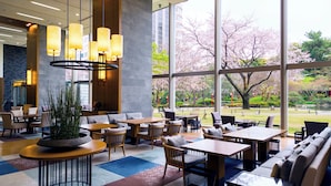 A modern indoor space with large windows, a variety of seating arrangements, and a central plant. - Grand Prince Hotel Takanawa (Tokyo)