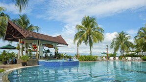 A pool area with a beach bar, lounge chairs, and palm trees. - Flamingo By The Beach Penang (George Town)