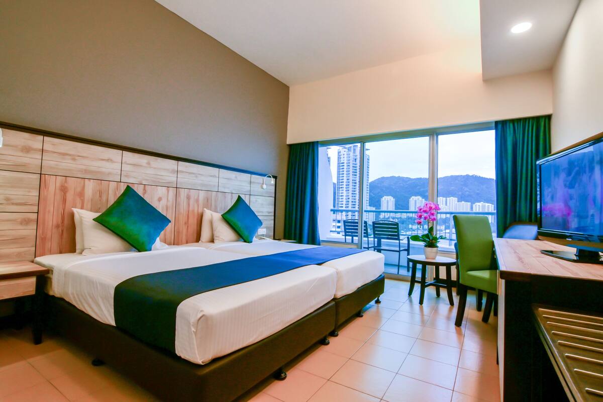 A hotel room with a large bed, a desk, and a view of the city.