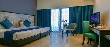 Ein Hotelzimmer mit Bett, Schreibtisch, Stuhl und Fernseher.