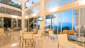 A modern hotel lobby with glass walls, a flat-screen TV, and a seating area with white and beige furniture. - Flamingo By The Beach Penang (George Town)