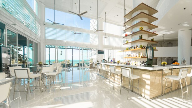 A spacious, modern kitchen with a central island, high ceilings, and large windows offering a view of the ocean. - Flamingo By The Beach Penang (George Town)