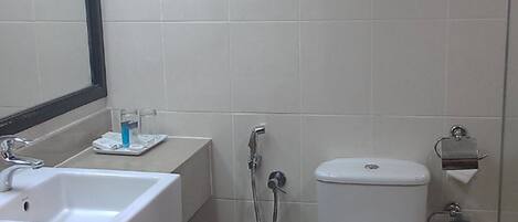 A bathroom with a sink, mirror, toilet, and towel rack.