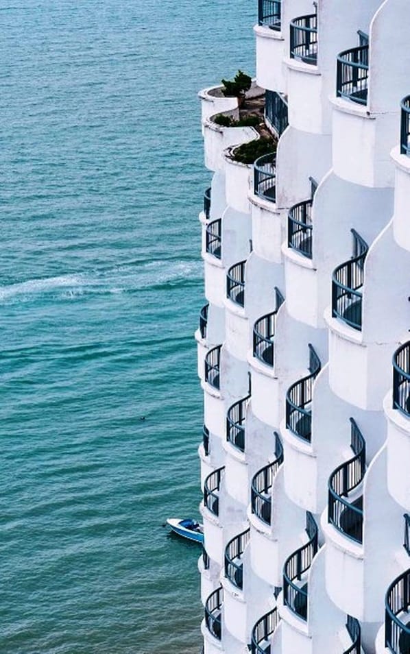 A high-rise hotel with multiple balconies overlooking a body of water. - Flamingo By The Beach Penang (George Town)