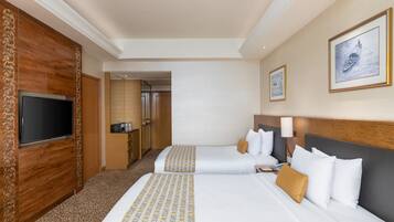 Habitación de hotel con dos camas, televisor, un panel decorativo de madera y cuadros en la pared.
