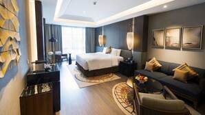 Una habitación de hotel moderna con una cama grande, un sofá, un escritorio y un comedor.