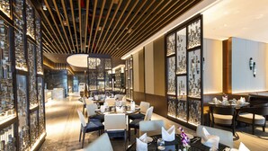 Un restaurante moderno con mesas dispuestas para comer, un techo decorativo y una pared con objetos enmarcados.