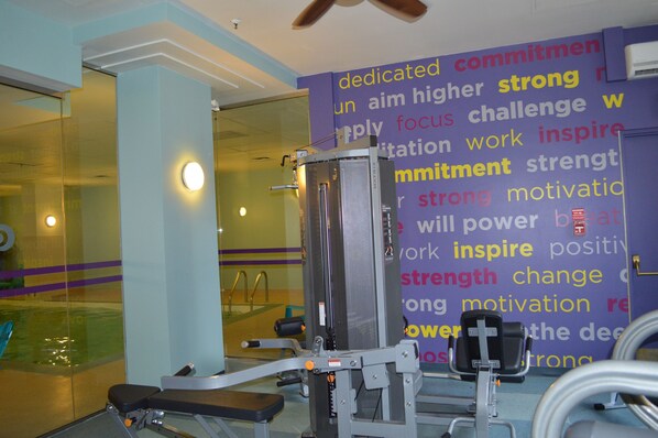 Un gimnasio con equipo de ejercicio y mensajes motivadores en la pared.