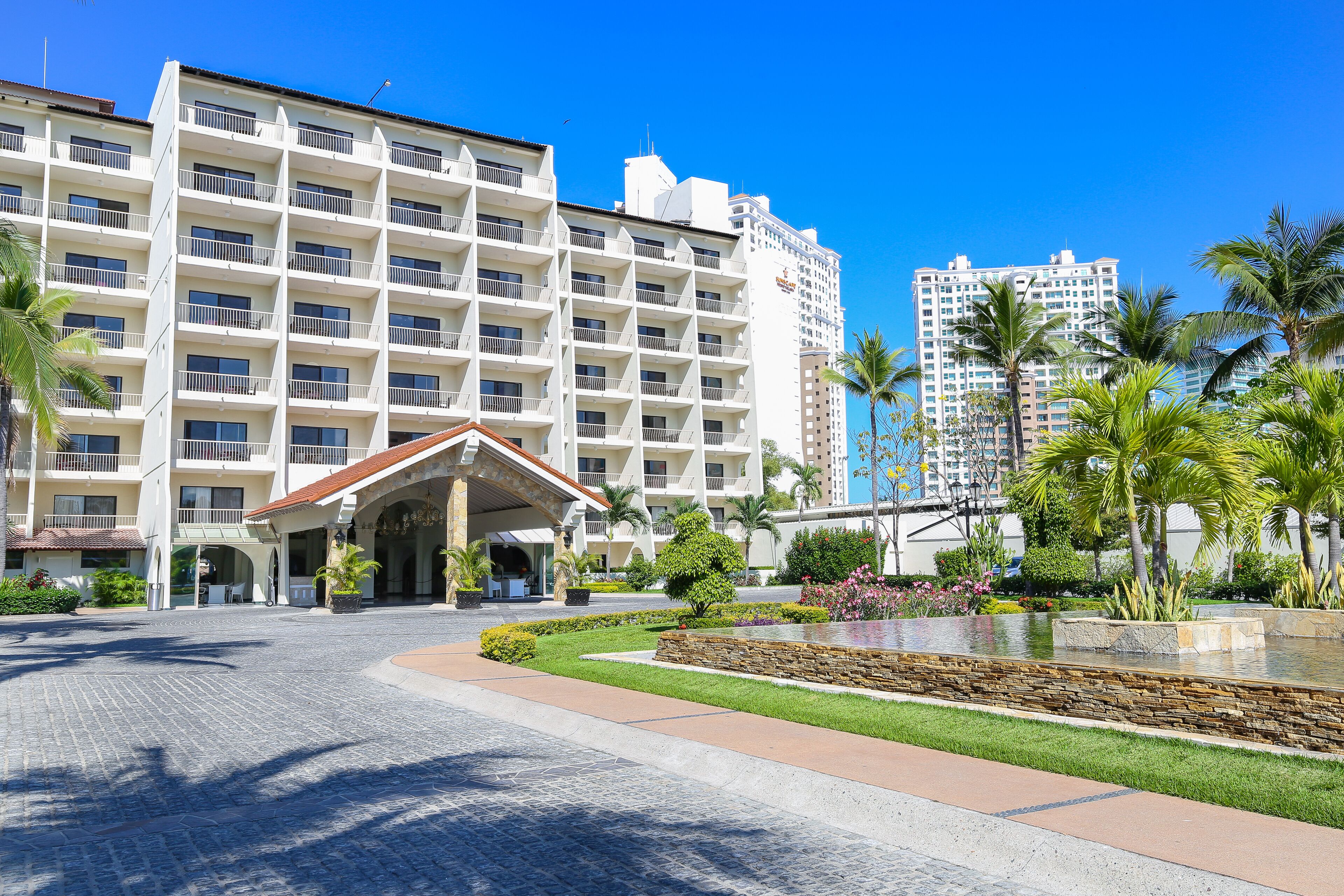 A hotel with a central courtyard, multiple floors, and a prominent entrance with a covered area.