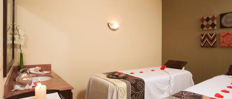 A room with two beds, a mirror, a sink, and a candle.