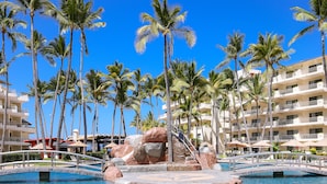 A resort pool area with palm trees, a bridge, and a building with balconies. - Villa del Palmar Beach Resort and Spa, Puerto Vallarta (Puerto Vallarta)