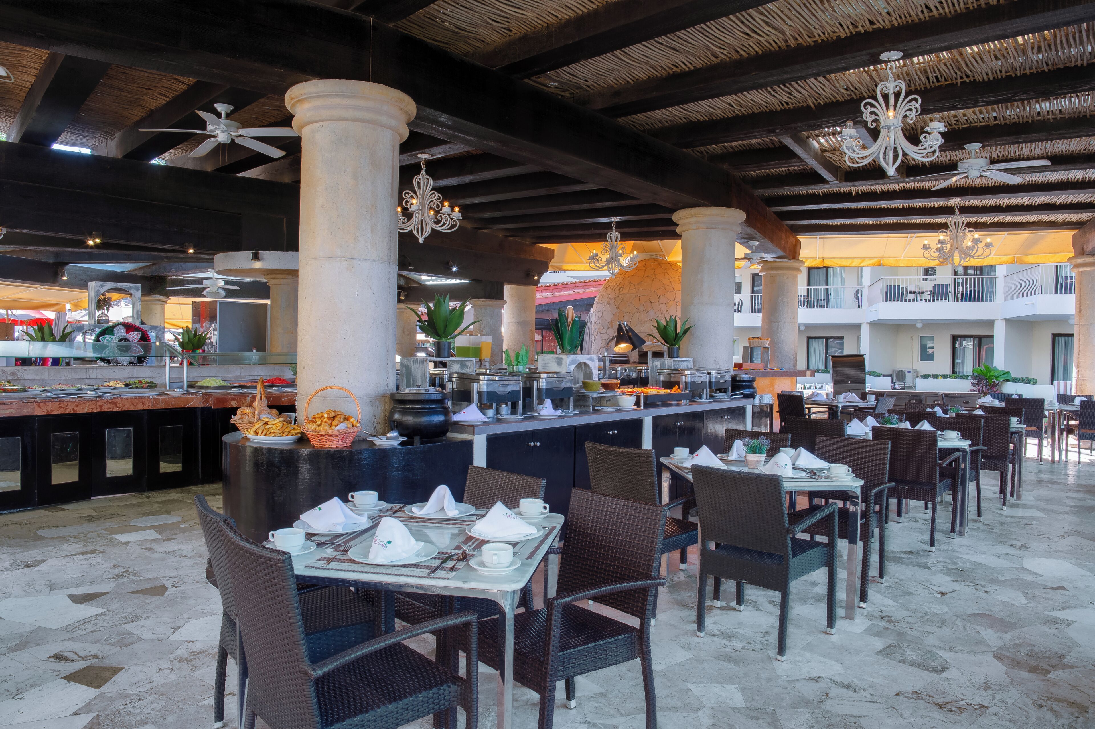 A restaurant with high ceilings, columns, and wicker furniture.