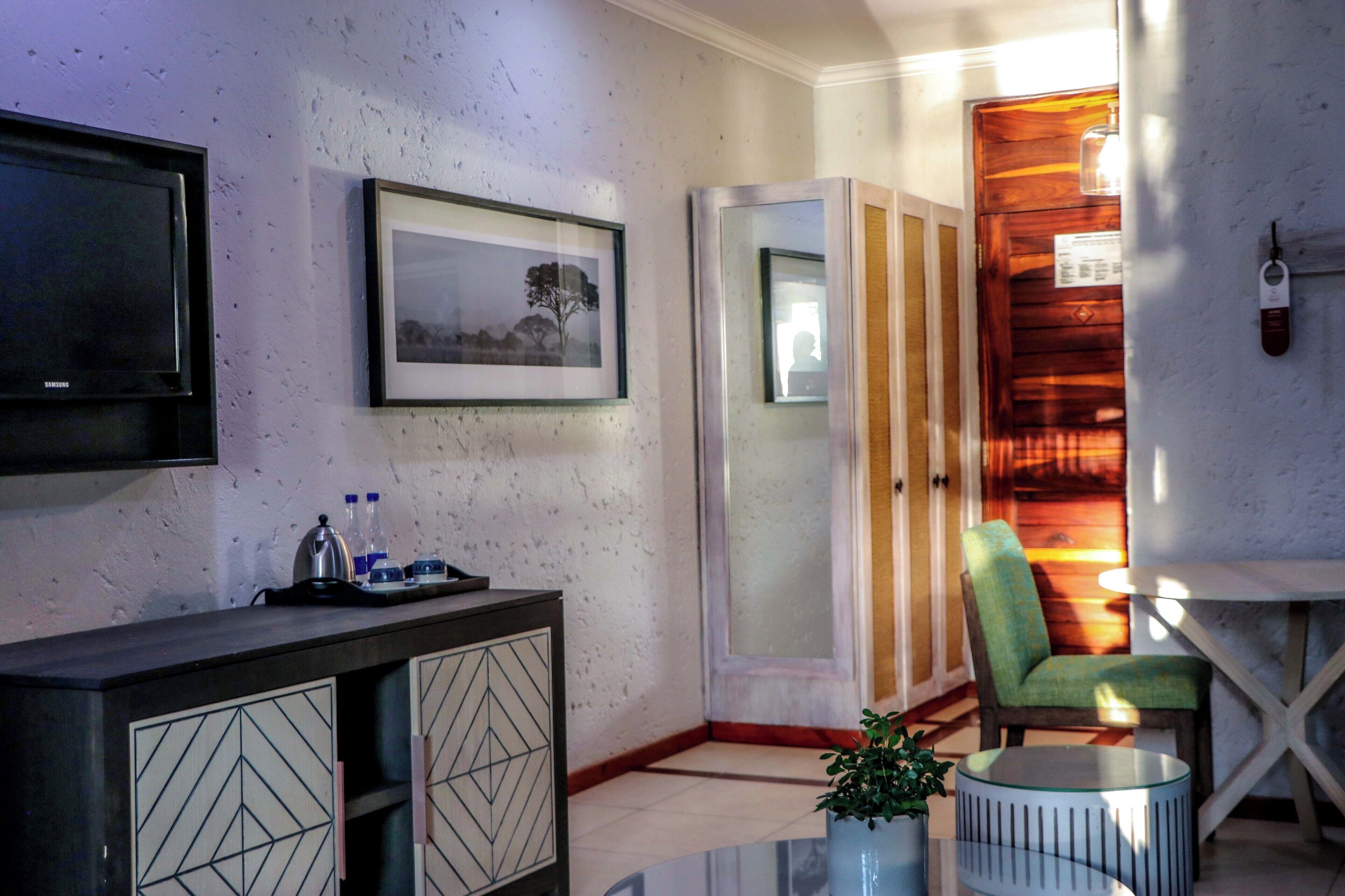 A room with a TV, framed pictures, a cabinet, a chair, a small table, and a potted plant.