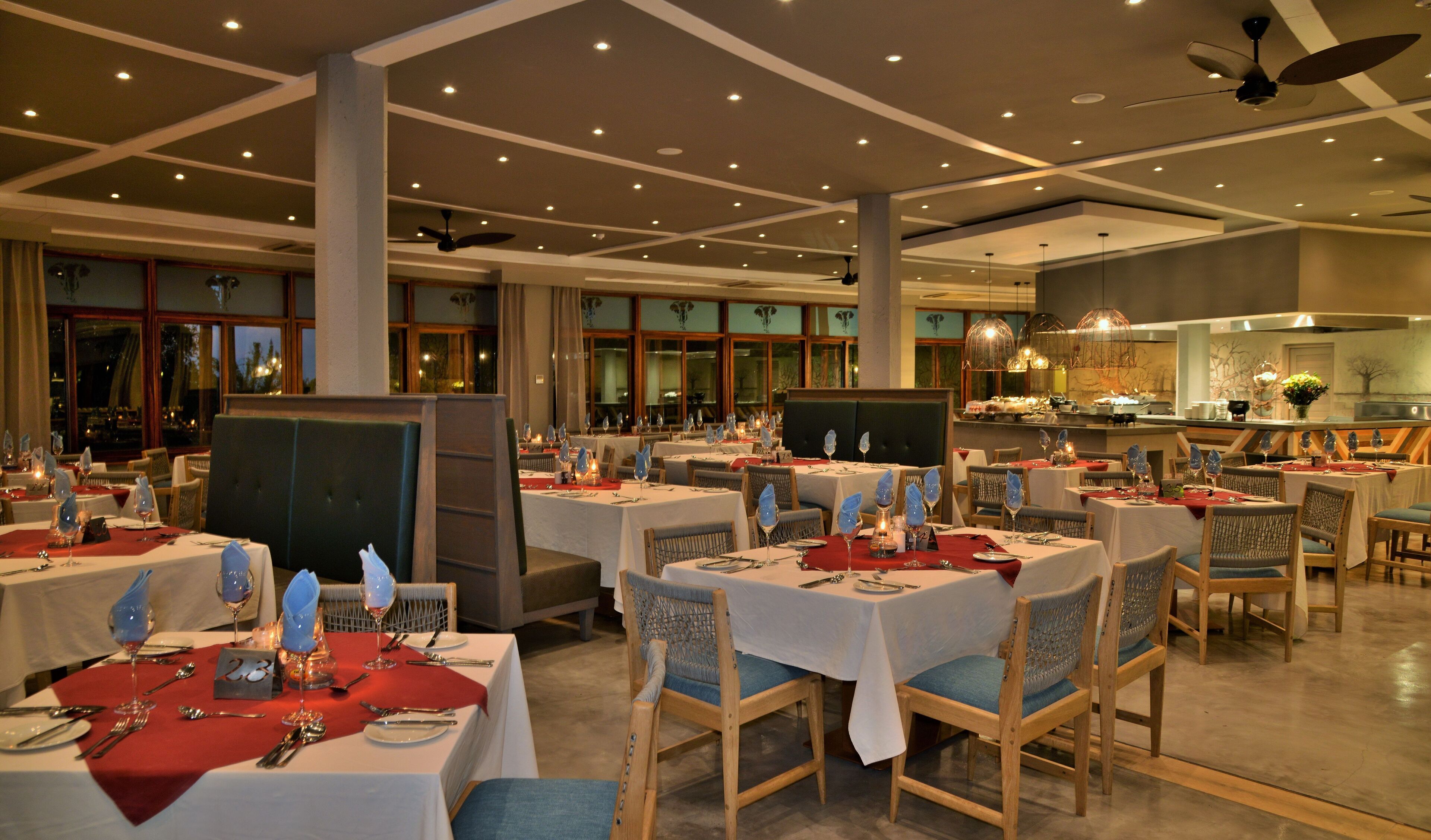 A restaurant with multiple tables set for dining, featuring a modern interior with ceiling fans and recessed lighting.
