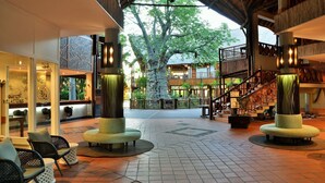 Un vestíbulo amplio con una zona de estar central, una escalera y vistas a un árbol exterior.