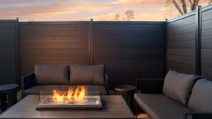 An outdoor seating area with a fire feature, cushioned seating, and a view of the sky. - Springhill Suites Marriott Little Rock West (Little Rock)