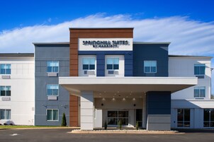 Un hotel moderno con un cartel que dice "Springhill Suites by Marriott". Cuenta con una estructura de dos pisos, techo plano y entrada cubierta.