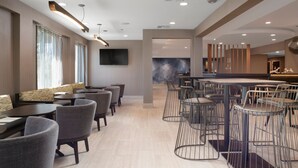 A modern hotel lobby with a bar area, seating arrangements, and a large wall-mounted TV. - Springhill Suites Marriott Little Rock West (Little Rock)