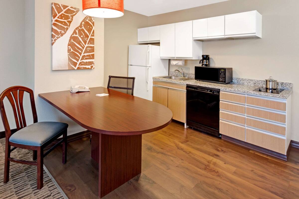 A compact kitchen with white cabinets, a microwave, a coffee maker, and a dishwasher.