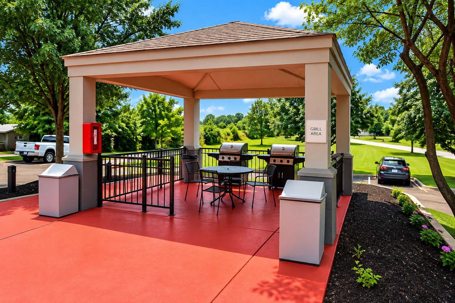 A covered outdoor patio with barbecue grills, seating, and trash bins.