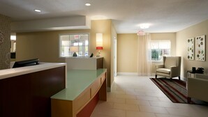 A reception area with a counter, a chair, and a lamp. - MainStay Suites Detroit Farmington Hills (Farmington Hills)