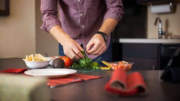 Una persona preparando comida con verduras y papas fritas sobre una mesa.