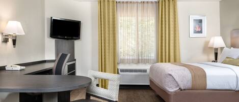 Une chambre d’hôtel équipée d’un lit, d’un bureau, d’une chaise, d’une télévision et d’une fenêtre avec des rideaux.