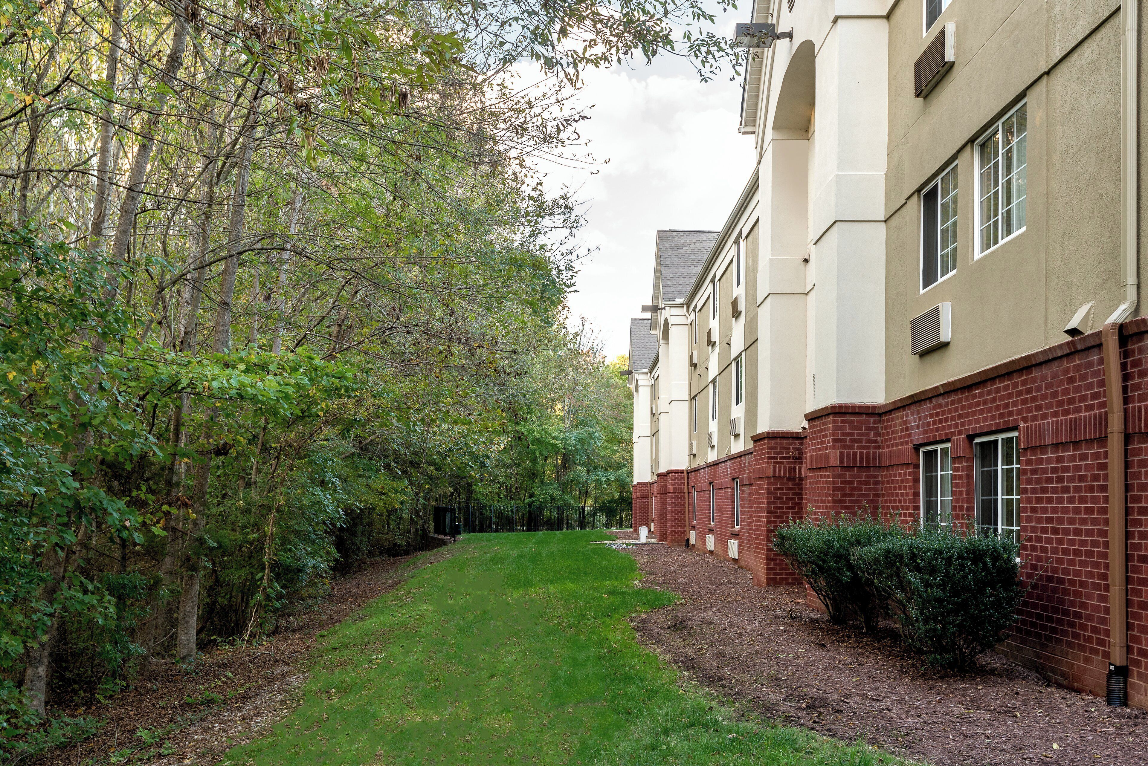 A pathway leading to a building with a brick facade and a green lawn.