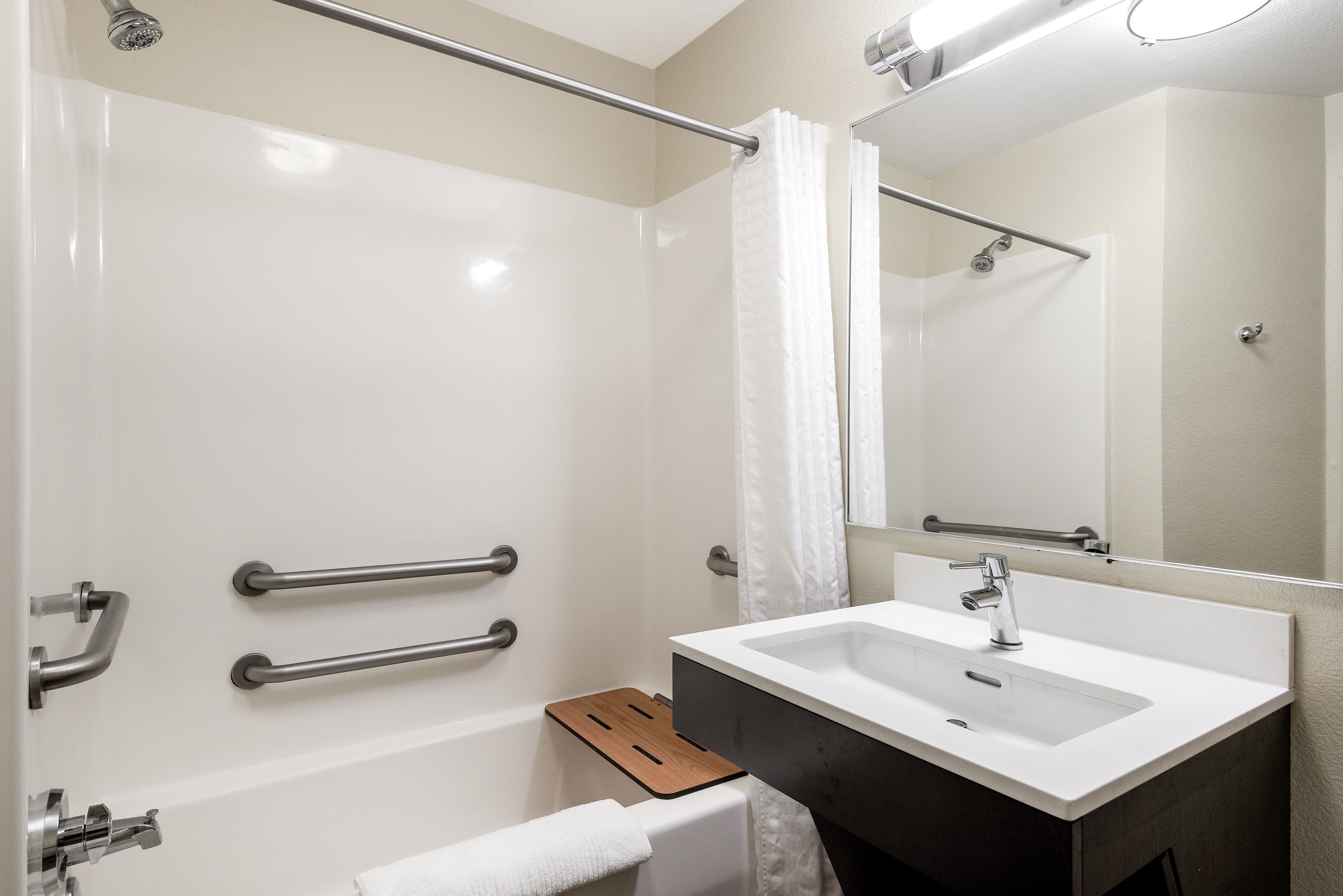 Un baño moderno con una bañera blanca, un lavabo con encimera oscura y un espejo sobre el lavabo.